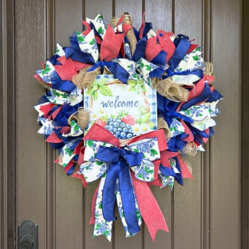 summer mesh wreath in red white and blue with a welcome sign with strawberries and blueberries