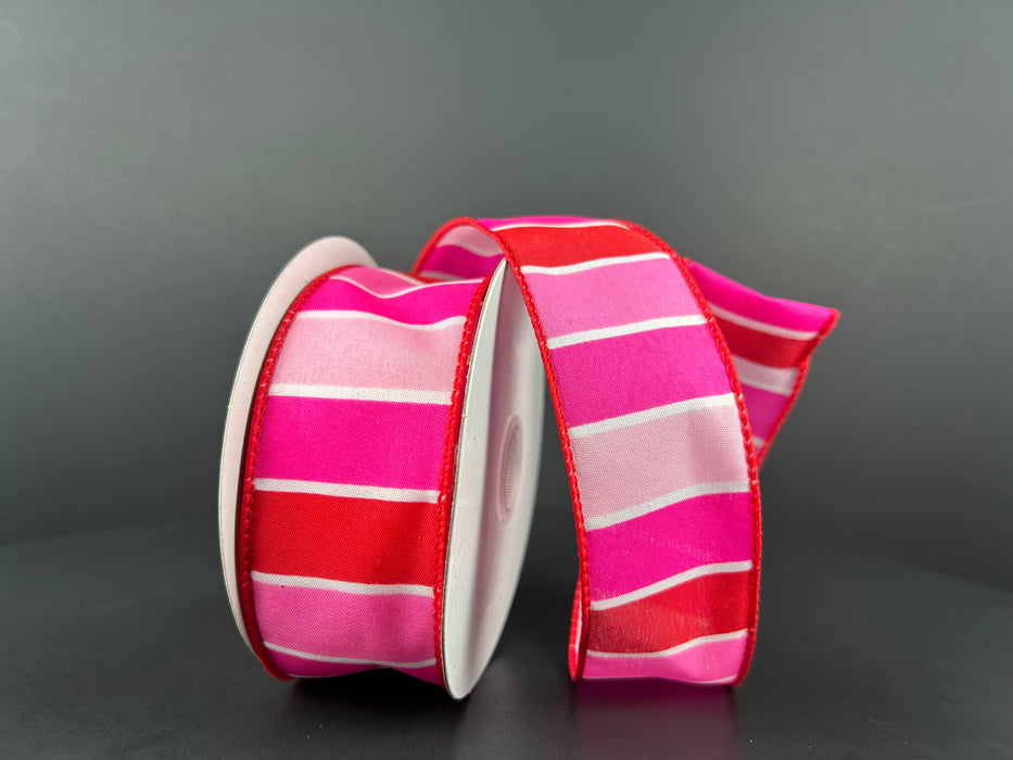 Two rolls of the Fuchsia-Red-Pink-White Wide Stripes ribbon, measuring 1.5 inches by 10 yards (product number 11407-09-28), are displayed. They feature vibrant fuchsia and red colors accented with horizontal white stripes and are partially unrolled against a dark background.
