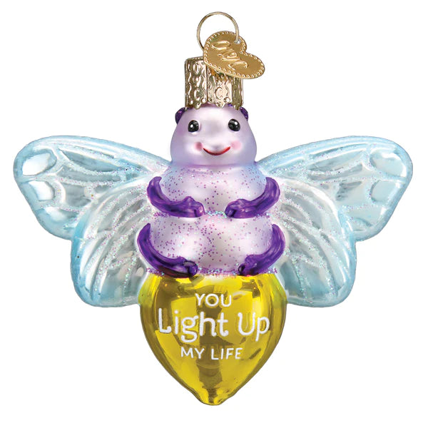 A vibrant, glittery mouth-blown glass ornament shaped like a smiling bee, featuring a purple and white body, blue wings, and a yellow heart-shaped bottom inscribed with "You light up my life." It's called the "You Light Up My Life Old World Christmas Ornament 12676," making it the perfect addition to your Christmas decorations with its convenient gold loop for hanging.