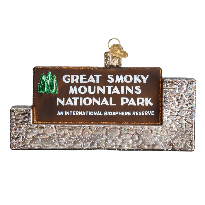 The Great Smoky Mountains National Park Old World Christmas Ornament 36189 is shaped like the park’s stone entrance sign, featuring white text, a green tree logo, and a gold loop—ideal for National Park and Appalachian Trail fans.