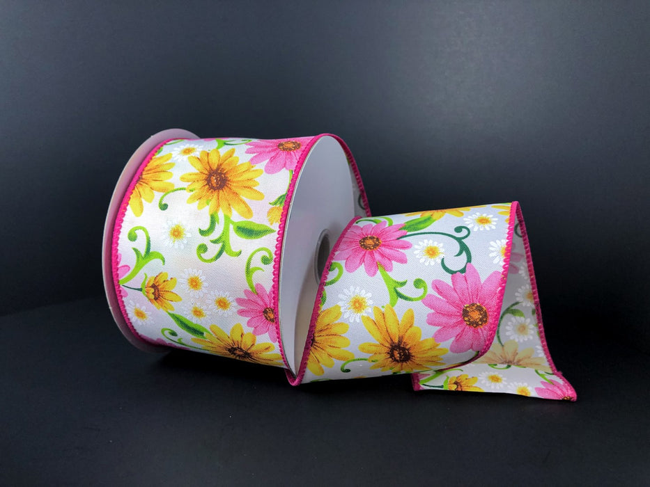 The 2.5X10Y White Pink Yellow Satin Daises Ribbon (41238-40-28) elegantly displays pink and yellow daisies with green stems and leaves on a white background, set against a darker backdrop when partially unrolled.