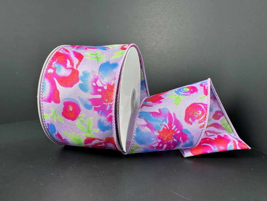 A 2.5x10YD ribbon with watercolor peonies in lavender blue, fuchsia, and orange blooms on a light gray background is partially unspooled on a dark surface.