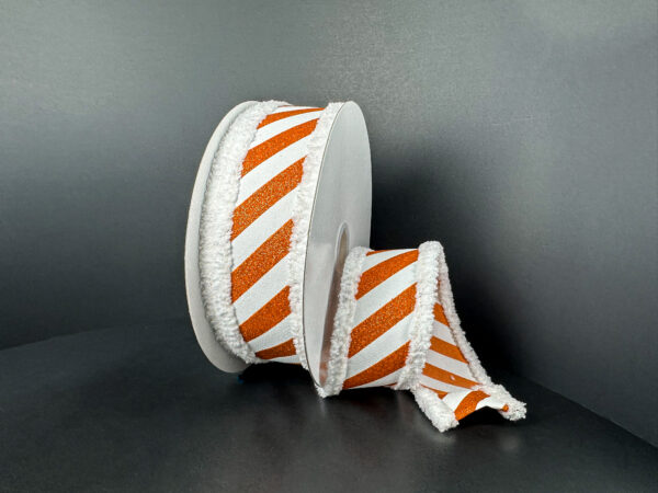 Two white circular boxes are decorated with 1.5x10Y orange flat all glitter/white diagonal stripe/white fuzz stripe ribbon (51503-09-01). One box is upright; the other lies on its side with ribbon cascading onto the surface.