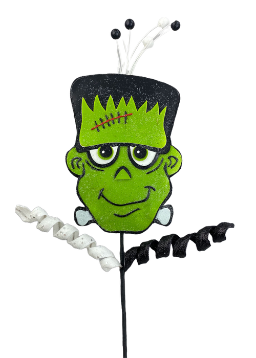 Introducing the 26" Green Frankie Pick 56961GN: a festive Halloween decoration showcasing a cartoonish, smiling green monster face complete with big eyes, a stitched forehead, and side bolts. The design is accentuated by its black felt top adorned with curled white and black ribbons extending from the back, adding an element of spooky charm.