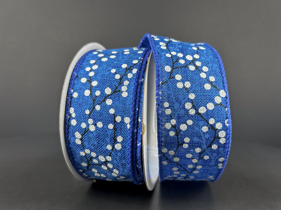A spool of 1.5X10Y Royal Blue Linen/White Glitter Berries ribbon sits against a dark background, partially unwound to reveal its elegant berry and branch design, adding a touch of sophistication.