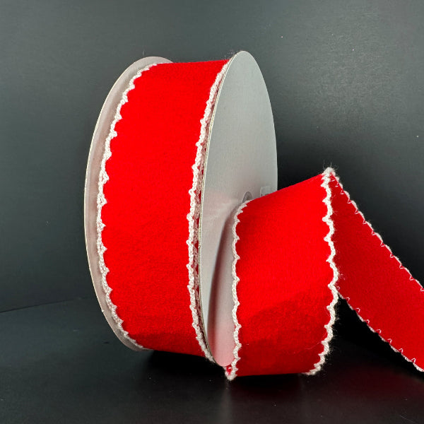A spool of 1.5X10Y Red Felt/White Scallop Edge Unwired Ribbon (73573-09-12) stands upright against a plain black background, with a length extending outward from the roll.