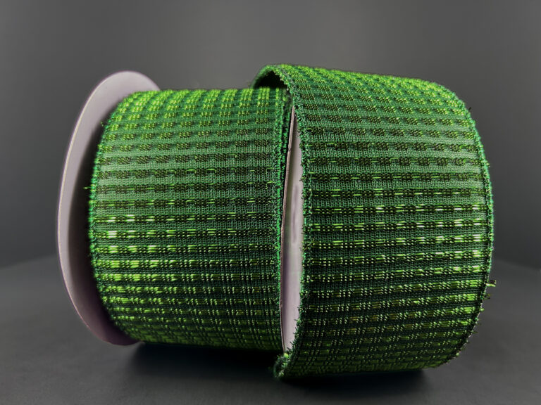 A close-up of a spool of 2.5X10Y Emerald Metallic Rishi Solid Ribbon (78496-40-17), featuring a wide, textured woven pattern, standing upright against a plain dark background.