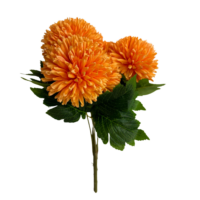 The 16 In Mum Bush X 7 84700-Or displays vibrant orange blooms on seven stems with lush green leaves, set against a white background. The chrysanthemum petals are full and layered, providing a rich, textured appearance.