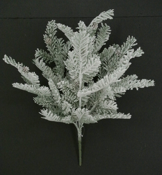 The 20" Snowed Pine Bush with 6 Stems (85287) features white-tipped artificial pine greenery and small pine cones, beautifully displayed against a plain black background.