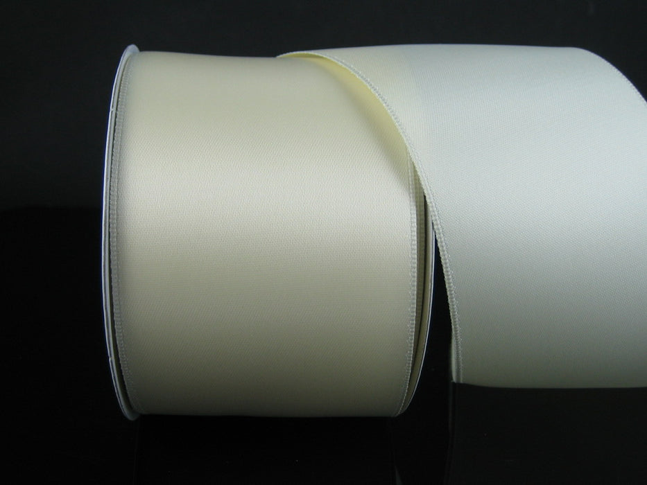 The 2.5 by 25 Yards Ivory Wired Double Faced Satin Ribbon 950140-18 is partially unrolled against a black background, showcasing its smooth, shiny satin texture.