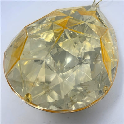 The 6.3" x 4" x 9" Gold Plastic Drop Ornament (DCORN5408GD) features a large, faceted teardrop shape with a reflective yellow-gold finish and elegant geometric patterns on its surface.
