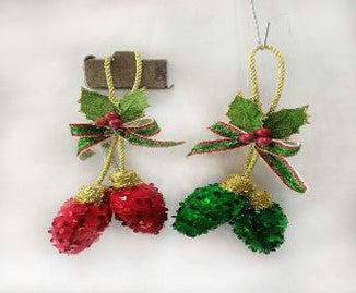 Two 7.5 Sequin Bulb Drop Ornaments (set of 2, MTX71997) with sparkly red and green pinecones, gold string loops, green leaves, red berries, and gold/red ribbons hang elegantly against a white background.