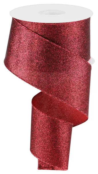 A partially unspooled 2.5X10YD Cranberry Shimmer Glitter Ribbon (RGC1597Y6) is coiled in a spiral, displaying its sparkling, glittery material as it winds around a white spool.