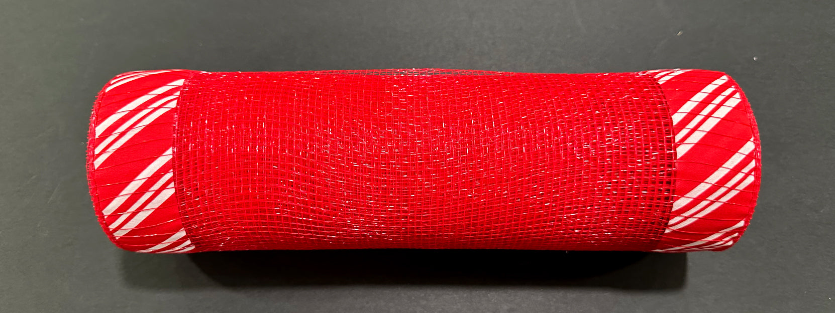 A 10X10Y Red Mesh/Candy Cane Print Ruff Edge (XB254010-01) is displayed on a dark surface, featuring red mesh with ruff edge and diagonally striped red and white ends.