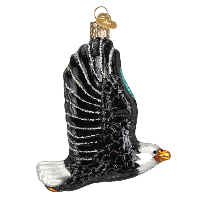 The Eagle In Flight Ornament (Old World Christmas Ornament 16122) features a striking bald eagle with black wings, white head, yellow beak, and gold cap—an eye-catching addition to your holiday décor.