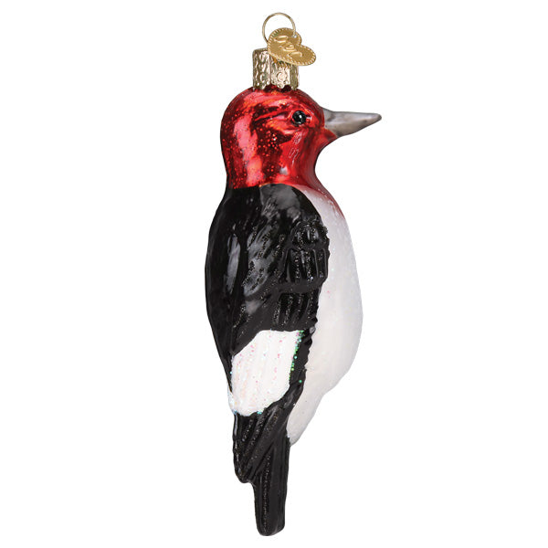 The Red-headed Woodpecker Ornament (Old World Christmas 16140) features a red head, black wings and back, a white belly, and a gold cap with loop—ideal for bird lovers and festive décor.