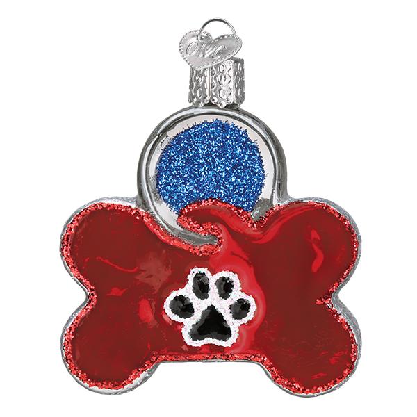 The Dog Tag Ornament Old World Christmas Ornament 32402 features a shiny red finish, black and white paw print center, blue glittery circle at the top, and a silver hanging loop—perfect for personalizing your tree.