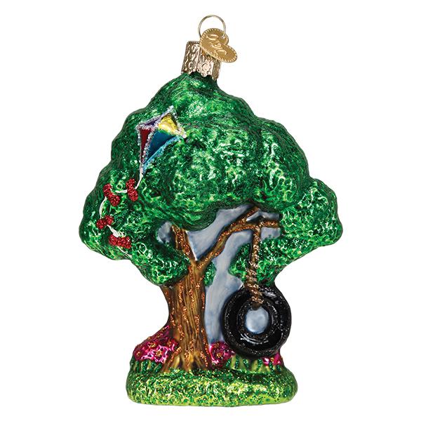The Tire Swing Old World Christmas Ornament 36267 is a hand-painted glass piece shaped like a leafy green tree with a kite, tire swing, and red flowers, completed with a golden hanging loop.