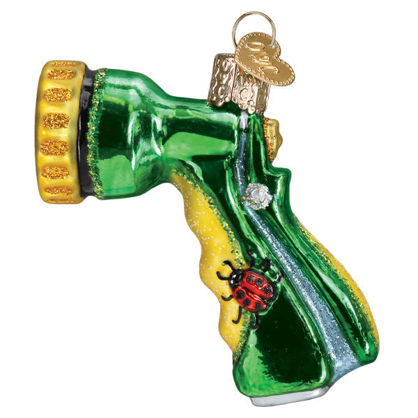 The Garden Hose Nozzle Ornament by Old World Christmas (36306) features shiny green and yellow colors, a gold glittered tip, a red ladybug on the handle, and a gold hanging loop—perfect for any gardening enthusiast’s collection.