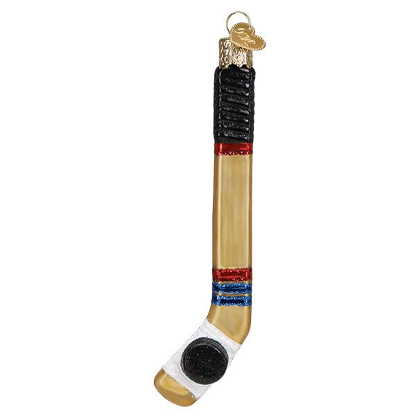 The Hockey Stick Old World Christmas Ornament 44155 is a hand-painted glass ornament featuring a black puck at the blade, red, blue, and black accents, and a gold cap with loop for hanging.
