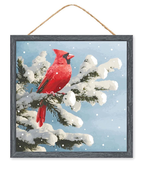 The 10Sq MDF Cardinal On Snowy Branch (Lt Blue/Red/White/Grey, AP7151) features a bright red cardinal on a snowy branch with a blue sky, framed and hung by brown string for rustic charm in any space.