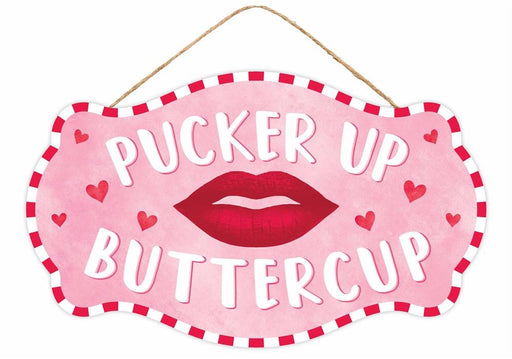 The 12.5L X 7.5H Pucker Up Buttercup sign (AP7172) has a light pink background with a striking red border, small red hearts, and bold white letters surrounding an illustration of red lips. It hangs invitingly from a string.