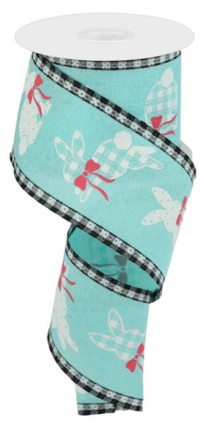 A spool of 2.5" x 10 yards ribbon called "Bunnies On Royal/Check Ice Blue/White/Pink" features a design with white bunnies wearing red bows, set against an ice blue background and edged with a black and white checkered pattern.