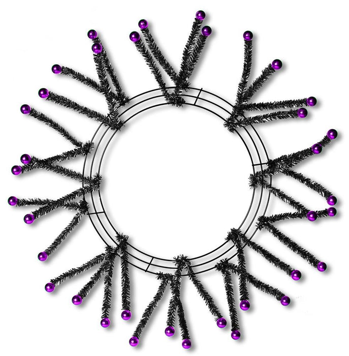 The 24 Black Metallic Pencil Wreath XX751564 features spiky tinsel branches tipped with shiny purple balls, creating a striking starburst effect on a white background.