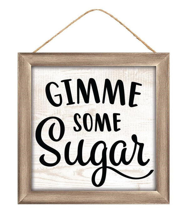 The 10Sq MDF Gimme Some Sugar Sign (AP7167) features bold black lettering on a white background with a wooden frame in light brown and beige, and hangs easily by a twine string.