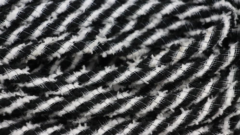 The 8Mm X 20Yd Snowdrift Deco Flex Tubing Black/White RE3225K2 features black and white diagonal stripes in a textured, woven design reminiscent of snowdrifts, creating a dynamic visual appeal.