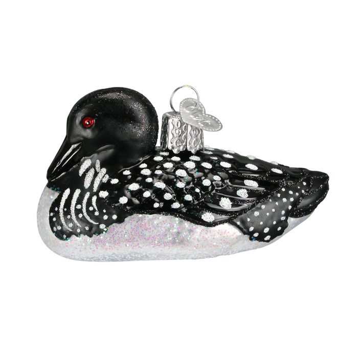 The Loon 16056 Old World Christmas Ornament is a hand painted glass piece depicting a black and white loon with red eyes, speckled wings, and a metallic hanging cap.
