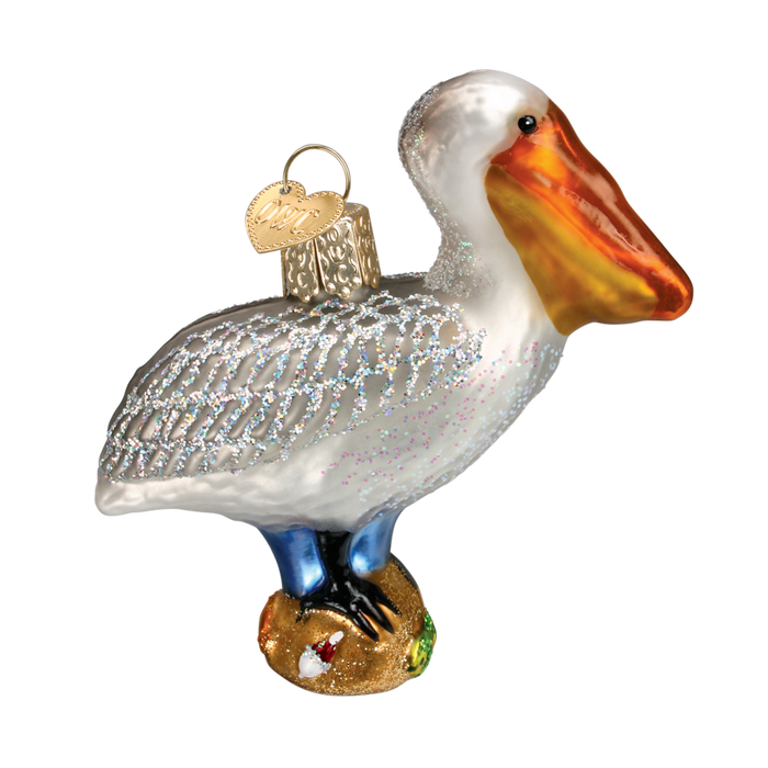 The Pelican 16073 Old World Christmas Ornament is a collectible glass ornament with blue legs, an orange beak, silver glittered feathers, a gold base, hanging loop, and gold heart tag—perfect for festive decor.
