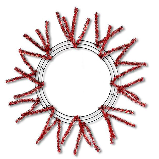 A 24" Pencil Work Wreath Metallic Red (XX751124) frame features vibrant red tinsel branches spreading outward in a sunburst pattern, beautifully contrasting against a white backdrop.