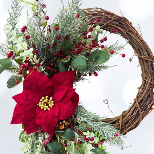 grapevine wreath with winter greenery, red poinsettia and red berries
