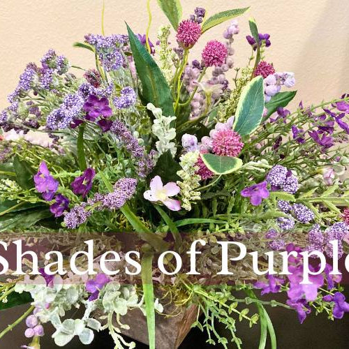 shades of purple artificial flowers in a small wooden container