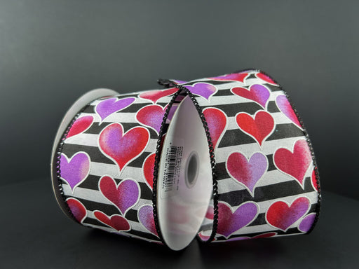 Two rolls of the product "Black And White Satin Stripe/Red-Pink-Lavender Ombre Hearts, 2.5\"X10Y 11416-40-30" are showcased against a dark background.