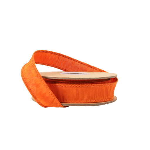 A spool of 1" Pumpkin Dupioni Ribbon (9100W-752-25E) with stitched edges, partially unspooled and wound on a flat cardboard holder, sits against a plain white background.