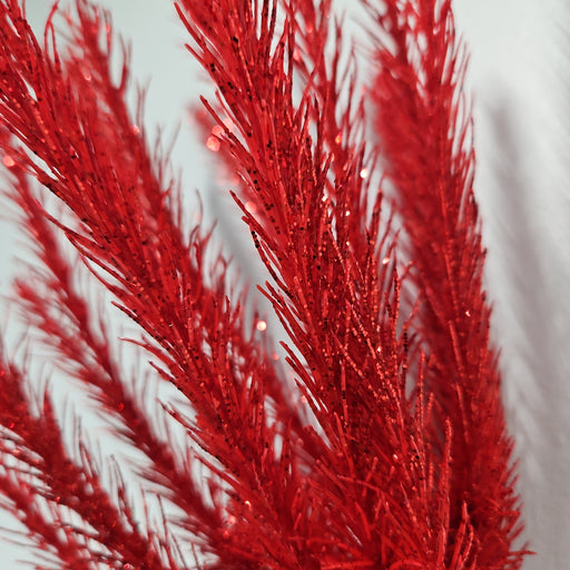 Close-up of the vibrant 16" Red Christmas Salix 83552-RD, featuring feathery branches against a white background, highlighting its detailed texture and slightly shimmering appearance.