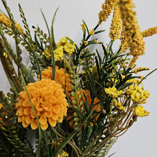 A bouquet featuring yellow and orange Yellow Dahlia, marigolds, small yellow blooms, and green foliage with Foxtail Bush is beautifully displayed against a plain white background.