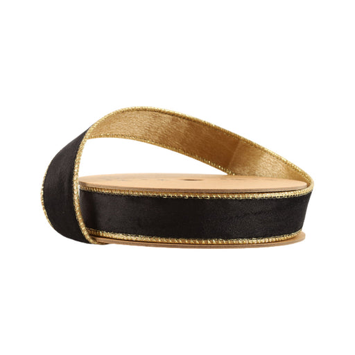 A spool of 1" Black and Gold Reversible Classic Velvet Ribbon (7115W-030-25E), featuring black velvet with shiny gold edges, partially unspooled and coiled around a circular cardboard reel.