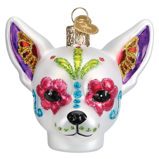 The Dia De Los Muertos Dog Ornament Old World Christmas 26097 is a white ornament adorned with vibrant, glittery patterns inspired by the Mexican Day of the Dead celebration and Old World Christmas traditions, featuring flowers around the eyes and bright colors on the ears and forehead.