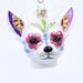 The Dia De Los Muertos Dog Ornament Old World Christmas 26097 is a white dog ornament adorned with colorful, glittery designs in a Day of the Dead style, featuring pink flowers, blue swirls, and gold accents on its face and ears. This unique Mexican holiday ornament captures the festive spirit and vibrant artistry celebrated by Old World Christmas.