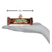 A Milky Way Old World Christmas Ornament 32609 glass ornament, shaped like a candy bar and measuring four inches wide, resting on a person’s open palm.