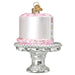 Cake on a Stand Old World Christmas Ornament 32618, shaped like a white cake with pink icing on a silver pedestal stand, featuring a small heart-shaped charm at the top.