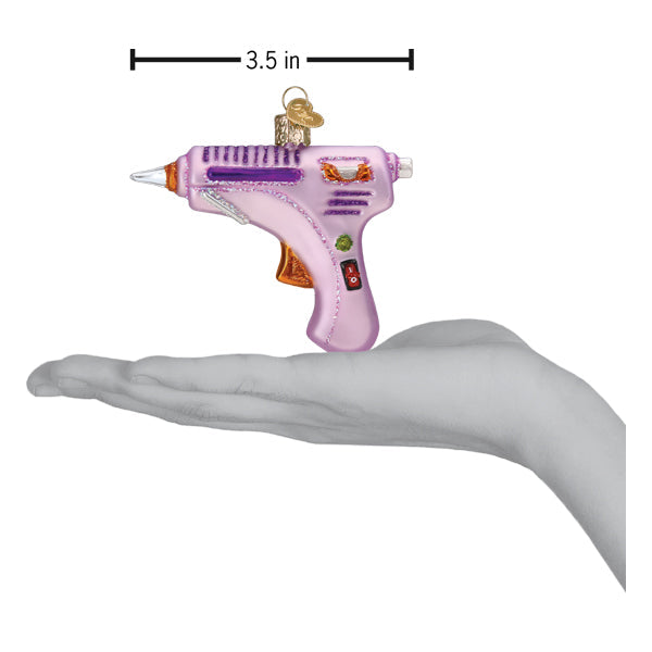 A hand holds a 3.5-inch pink Hot Glue Gun Old World Christmas Ornament 32629.