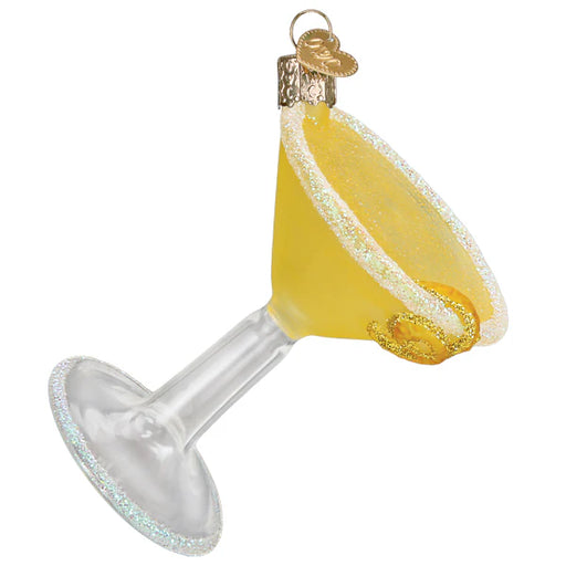 The Lemon Drop Martini Old World Christmas Ornament 32631 showcases a golden martini glass adorned with sparkly accents. It features a silver cap with a loop for hanging and is cleverly tilted to highlight its intricate details.