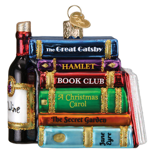 Book Club Old World Christmas Ornament 32653, a glass ornament shaped as a stack of books titled The Great Gatsby, Hamlet, Book Club, A Christmas Carol, The Secret Garden, and Jane Eyre, sitting next to a wine bottle.