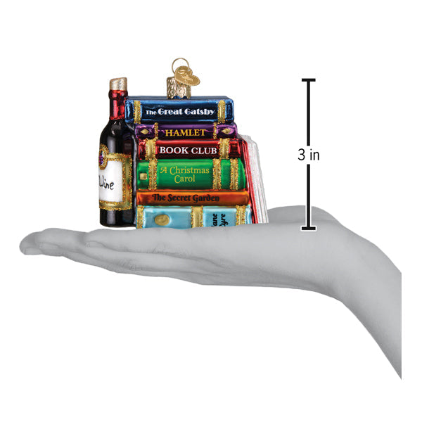 A hand holds a stack of colorful Book Club Old World Christmas Ornament 32653 pieces alongside a wine bottle ornament and a 3-inch measurement scale.