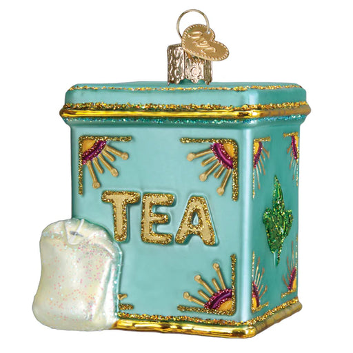 The Tea Tin Old World Christmas Ornament 32654 combines a vintage teal design with gold trim and colorful accents. TEA shines in gold letters, and a glittering white tea bag hangs on the side, adding charm.