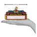 A hand holding a Broadway Marquee Old World Christmas Ornament 36345, shaped like a marquee measuring 4.75 inches across with a blank white sign below the text.
